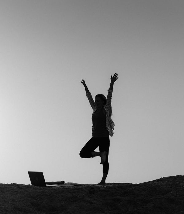 Silhouette of a person in a powerful yoga warrior pose against a sunrise.